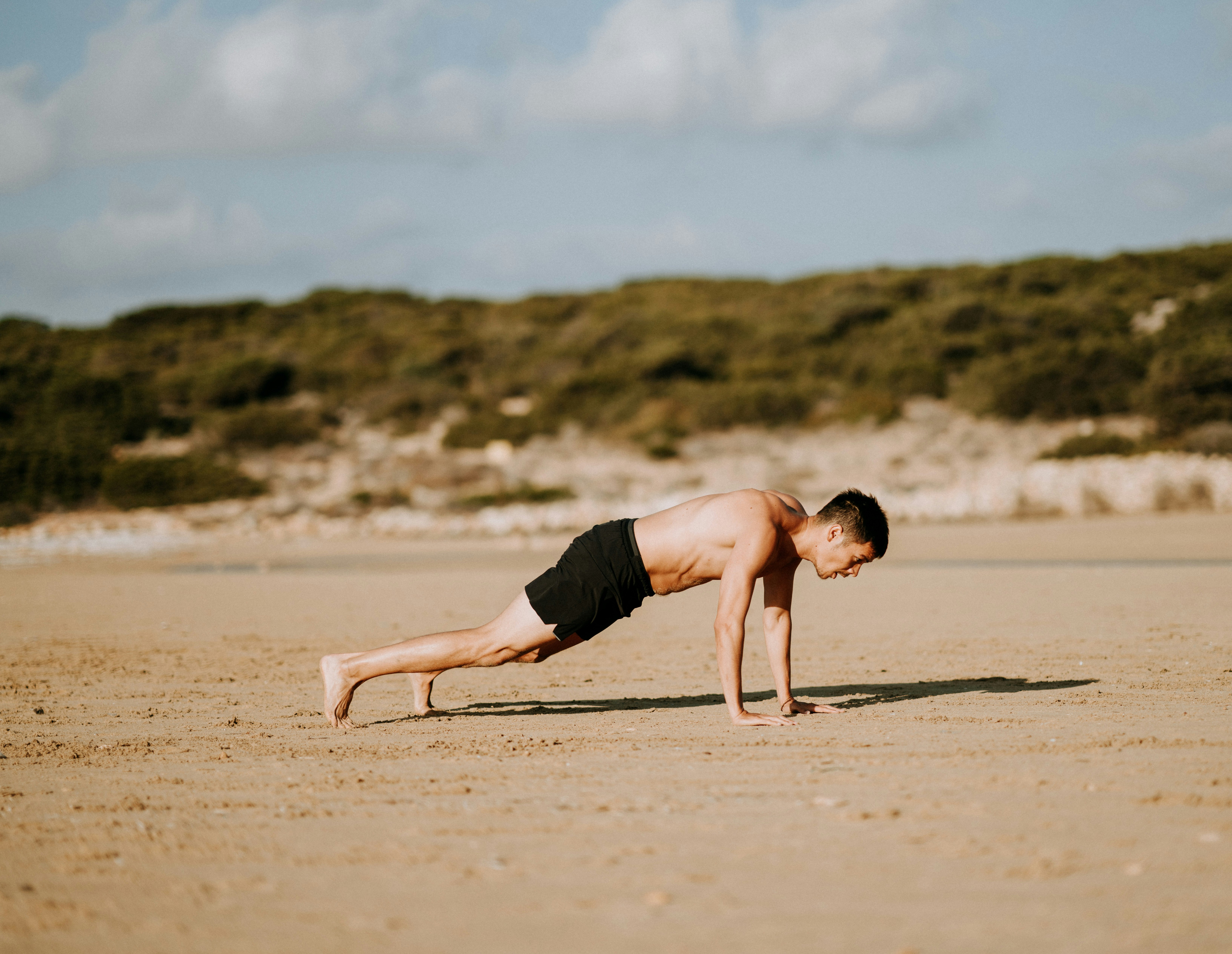 man doing push up on sand